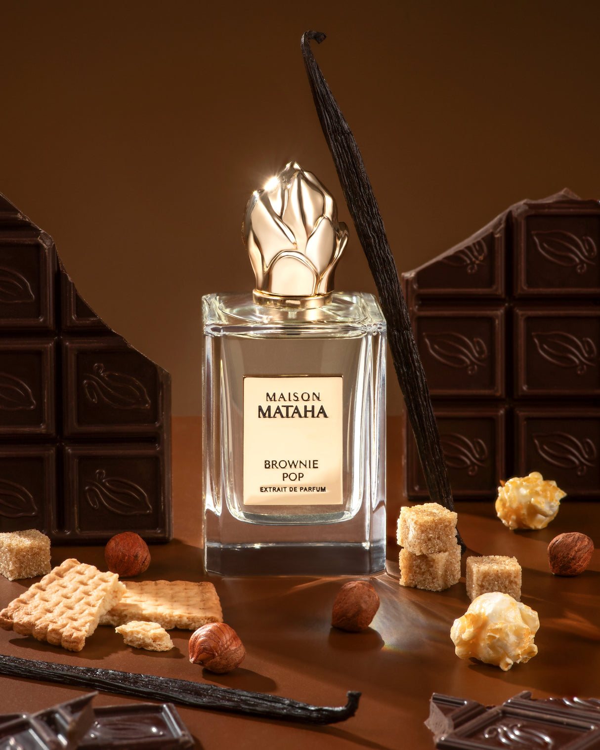 Brownie Pop Extrait de Parfum by Maison Mataha is pictured with chocolate squares, sugar cubes, vanilla beans, hazelnuts, biscuits, and caramelized popcorn—an irresistible gourmet scent for brownie fragrance lovers.