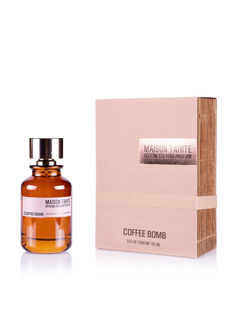 The Maison Tahite Coffee Bomb Eau de Parfum bottle, brown with a black cap, stands beside its beige box—both minimalist with white and metallic accents—embodying bold Italian coffee and warm amber notes.