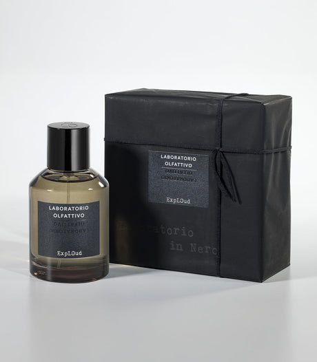 A bottle of ExplOud Eau de Parfum by Laboratorio Olfattivo, a woody oud scent, stands beside its sleek black box—both featuring minimalist black labels with white text.