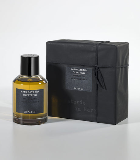 A bottle of Nerotic Eau de Parfum by Laboratorio Olfattivo sits beside its sleek black box, both displaying the brand’s name and scent in white on gray—an alluring unisex fragrance with rich amber notes.