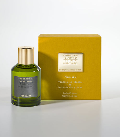A green glass bottle of Pompelmo Eau de Parfum by Laboratorio Olfattivo with a gold cap stands next to a yellow box, capturing the refreshing scent of Italian citruses and grapefruit.