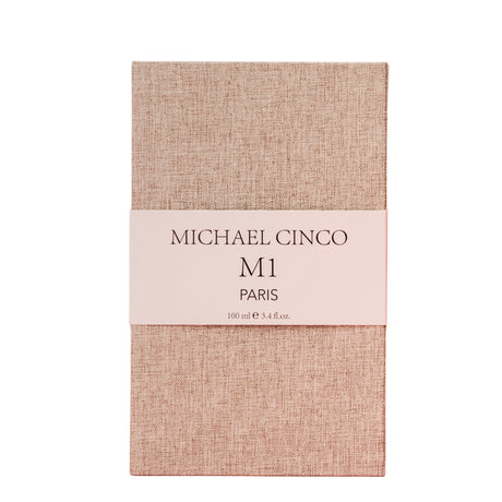 A beige textured rectangular box with a white band labeled Fragrapedia Haus M1 Eau de Parfum 100 ml, exuding a refined floral fragrance of rose and jasmine.