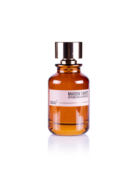 A brown glass bottle of Maison Tahite Cacao 2 Eau de Parfum, with a shiny gold cap and white label, is photographed on a white background, evoking an indulgent cocoa scent with extra dark chocolate notes.