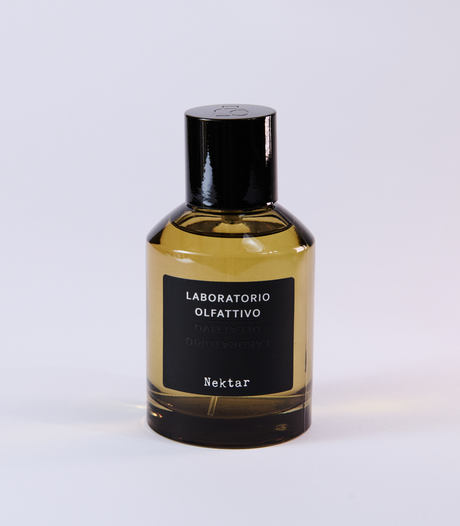 A bottle of Nektar Eau de Parfum by Laboratorio Olfattivo, featuring a black label and cap and inspired by the sweetness of Sidr Honey, displayed on a plain, light-colored background.