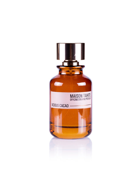 Maison Tahite's Vicious Cacao Eau de Parfum, in an amber glass bottle with a metallic cap, features rich cocoa absolute for a true gourmand fragrance and is displayed against a white background.