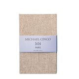A beige textured box with a light gray band displays Fragrapedia Haus M4 Eau de Parfum by Michael Cinco, 100 ml e 3.4 fl.oz., evoking a woody floral scent with delicate marine notes.