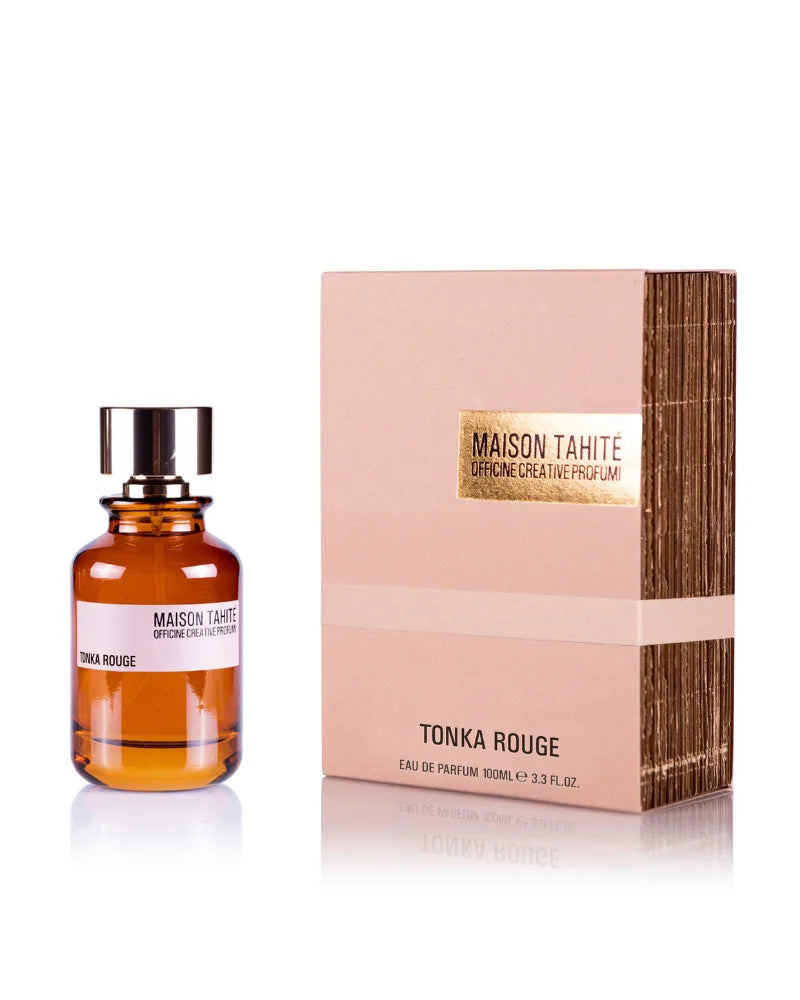 An amber-toned glass bottle of Maison Tahite Tonka Rouge Eau de Parfum sits beside a matching tan and gold box, both displayed against a white background.