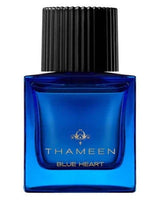 A square blue glass bottle of Fragrapedia Haus Blue Heart Extrait de Parfum by Thameen London, featuring a black ribbed cap and gold text on the front, reflects the allure of this ambery "blue diamond" fragrance.
