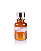 The Maison Tahite Coffee Bomb Eau de Parfum, in a brown glass bottle with a metallic cap, features rich Italian coffee and amber notes, presented against a white background.
