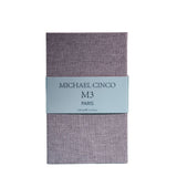 A rectangular box with a textured lavender surface and a light gray label reading Fragrapedia Haus M3 Eau de Parfum 100 ml, suggesting a floral scent created by Michael Cinco with consciously sourced ingredients.
