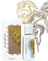 A white perfume bottle and box with gold abstract lion and geometric patterns. Cafe Kiss Eau de Parfum by Fragrapedia Haus is a cozy gourmand scent, shown with a gold and brown abstract background design.