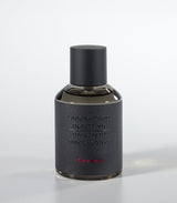 A dark, cylindrical Amberbomb Eau de Parfum bottle by Laboratorio Olfattivo features a matte black cap and textured gray label with silver brand text and red "Amberbomb," embodying the refined luxury of the Extreme Collection.