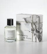 A clear bottle of Laboratorio Olfattivo's Decou Vert Eau de Parfum stands beside a floral-patterned box labeled Laboratorio in Fiore, both displayed on a white background.