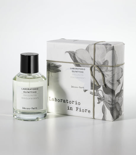 A clear bottle of Laboratorio Olfattivo's Decou Vert Eau de Parfum stands beside a floral-patterned box labeled Laboratorio in Fiore, both displayed on a white background.