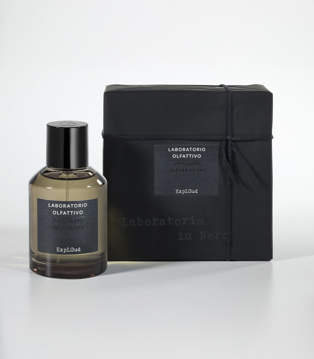 A bottle of Laboratorio Olfattivo ExplOud Eau de Parfum, known for its rich oud scent, stands beside a matching black box with branded labels, both arranged against a white background.