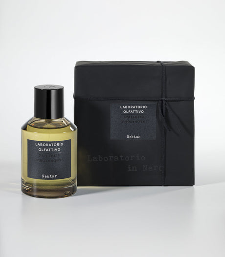 A bottle of Laboratorio Olfattivo Nektar Eau de Parfum with a black cap sits beside its matching black box, both adorned with white text, on a white background—an elegant homage to Sidr Honey and Wadi Darbat.