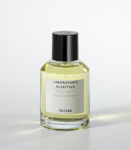 A clear glass bottle of Salina Eau de Parfum by Laboratorio Olfattivo, filled with yellow liquid and topped with a black cap, stands against a white background, capturing the fresh aquatic allure of this signature scent.