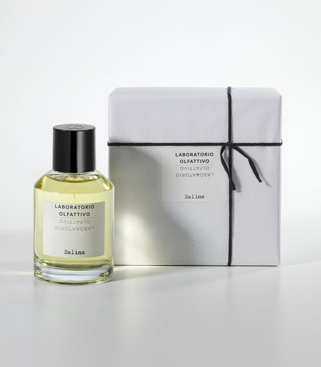 A clear glass bottle of Salina Eau de Parfum by Laboratorio Olfattivo stands beside a white, black-string-tied gift box, both set against a plain white background.