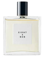 A clear glass men's perfume bottle from Fragrapedia Haus features a black cap and a white label reading "Eight and Bob." The pale yellow liquid inside is Eight and Bob Eau de Parfum, evoking an aromatic masculine scent.
