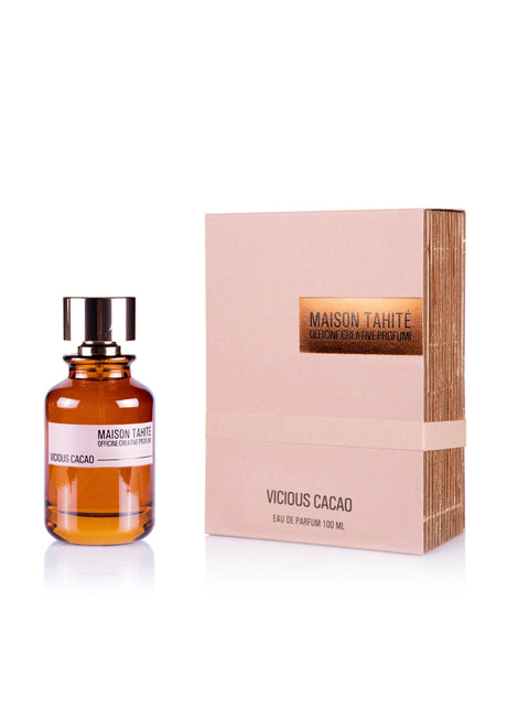 A brown glass bottle of Maison Tahité's Vicious Cacao Eau de Parfum with a black and gold cap sits next to its beige box, highlighting this gourmand fragrance by Maison Tahite enriched with rich cocoa absolute.
