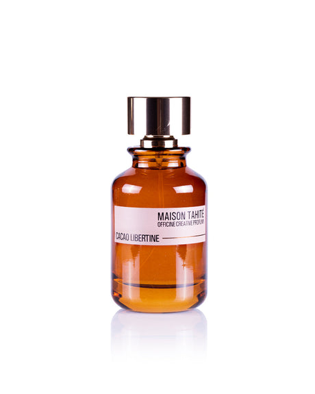 A brown glass bottle with a gold cap, labeled Maison Tahite Cacao Libertine Eau de Parfum, offers a gourmand scent ideal for vanilla and patchouli perfume lovers, shown against a white background.