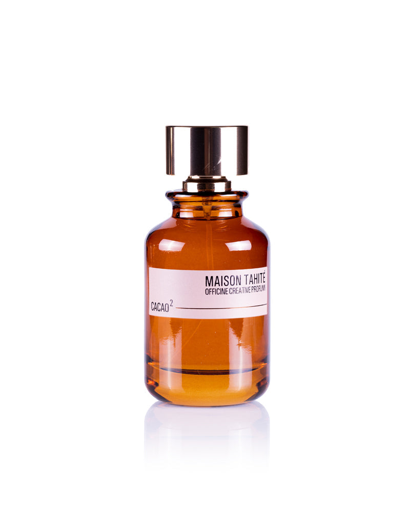 A brown glass bottle of Maison Tahite Cacao 2 Eau de Parfum, with a shiny gold cap and white label, is photographed on a white background, evoking an indulgent cocoa scent with extra dark chocolate notes.