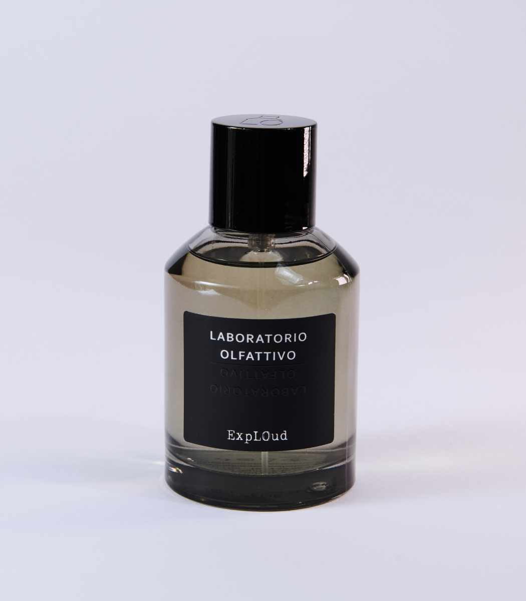 A clear glass bottle with a black cap and label reading "Laboratorio Olfattivo ExplOud Eau de Parfum" rests on a white background, emphasizing this woody, luxurious oud fragrance from Laboratorio Olfattivo.