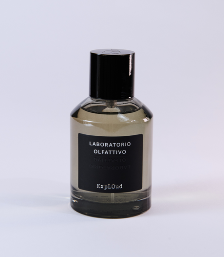 A clear glass bottle with a black cap and label reading "Laboratorio Olfattivo ExplOud Eau de Parfum" rests on a white background, emphasizing this woody, luxurious oud fragrance from Laboratorio Olfattivo.