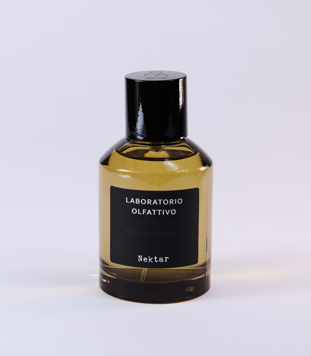 A bottle of Nektar Eau de Parfum by Laboratorio Olfattivo, featuring a black label and cap and inspired by the sweetness of Sidr Honey, displayed on a plain, light-colored background.
