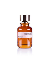 The Sel Vanille Eau de Parfum by Maison Tahite stands upright on a white background, its amber glass bottle with shiny gold cap reflecting the elegant blend of vanilla and sea salt fragrance within.