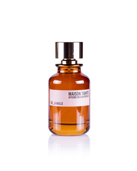 The Sel Vanille Eau de Parfum by Maison Tahite stands upright on a white background, its amber glass bottle with shiny gold cap reflecting the elegant blend of vanilla and sea salt fragrance within.