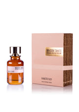 A 100 ml brown glass bottle of Maison Tahite Vanexstasy Eau de Parfum, featuring vanilla absolute, sits beside a matching beige and gold box. The bottle has a shiny silver cap and displays the Maison Tahite brand.