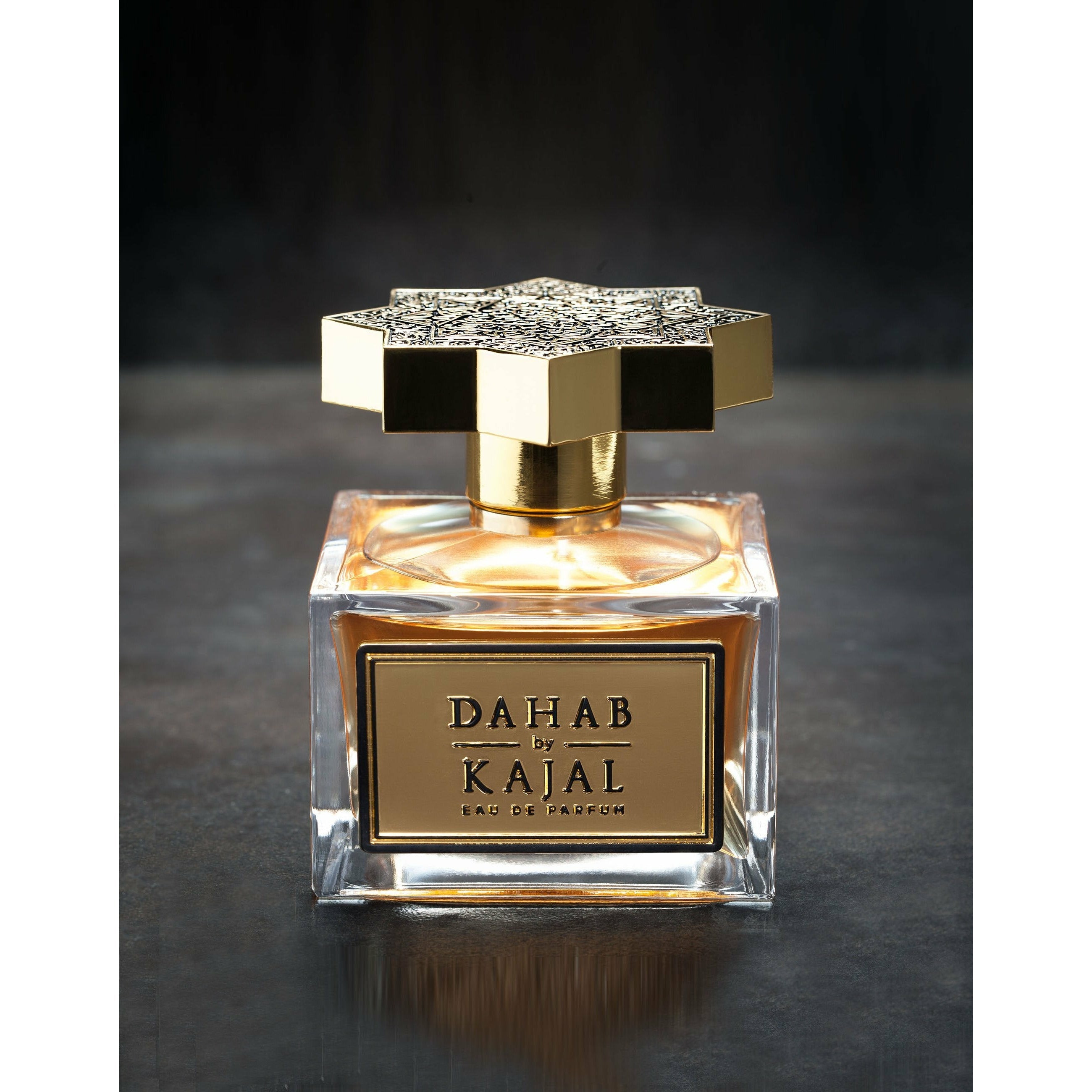 Clear glass cube bottle of Dahab 100ml with gold label and ornately engraved golden lid by Kajal perfumes.