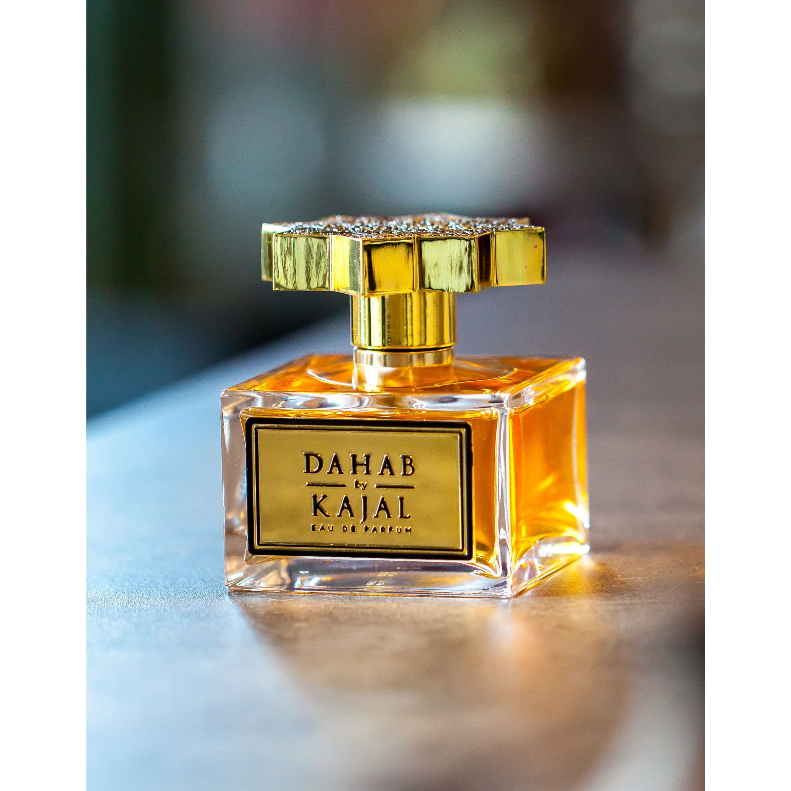 Clear glass cube bottle of Dahab 100ml with gold label and ornately engraved golden lid by Kajal perfumes.
