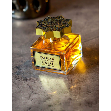 Clear glass cube bottle of Dahab 100ml with gold label and ornately engraved golden lid by Kajal perfumes.